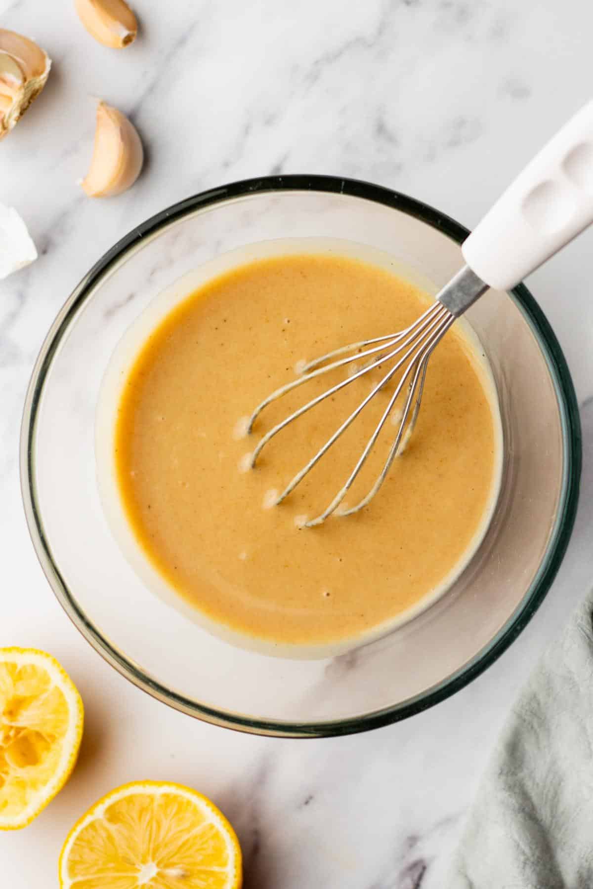 Whisking tahini dressing in a small bowl.