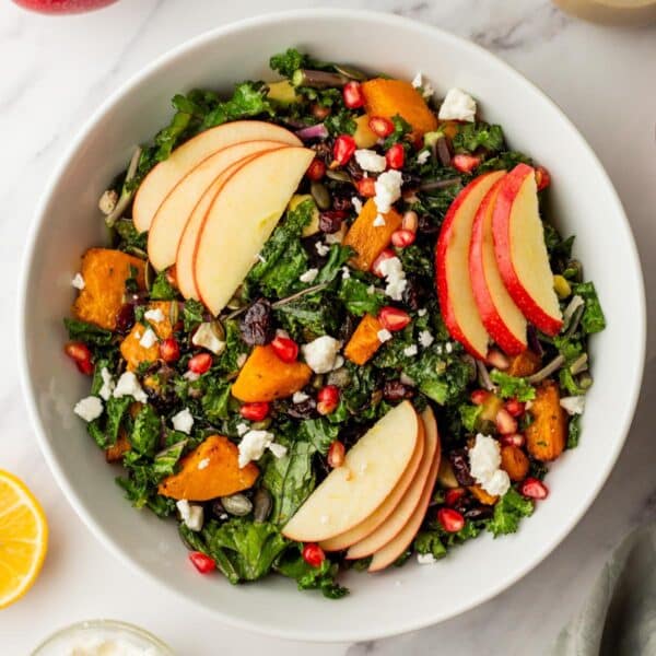 Butternut squash salad made with kale and topped with goat cheese and apple slices.