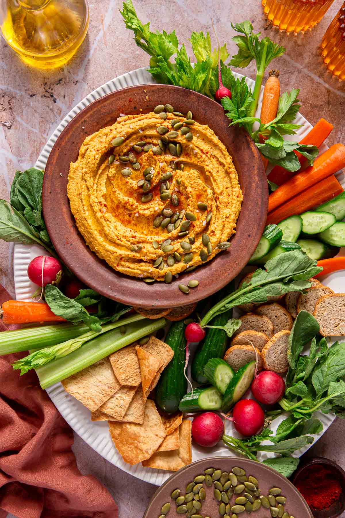 Pumpkin hummus topped with pumpkin seeds and served with raw veggies and crackers.