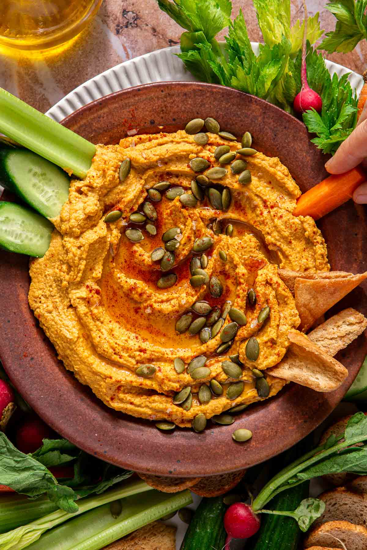 Dipping a raw carrot into pumpkin hummus.