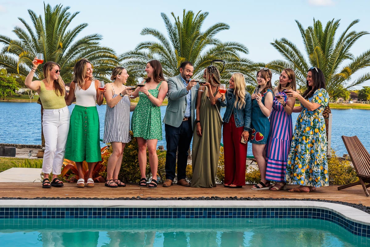 People near a pool with drinks in hand.