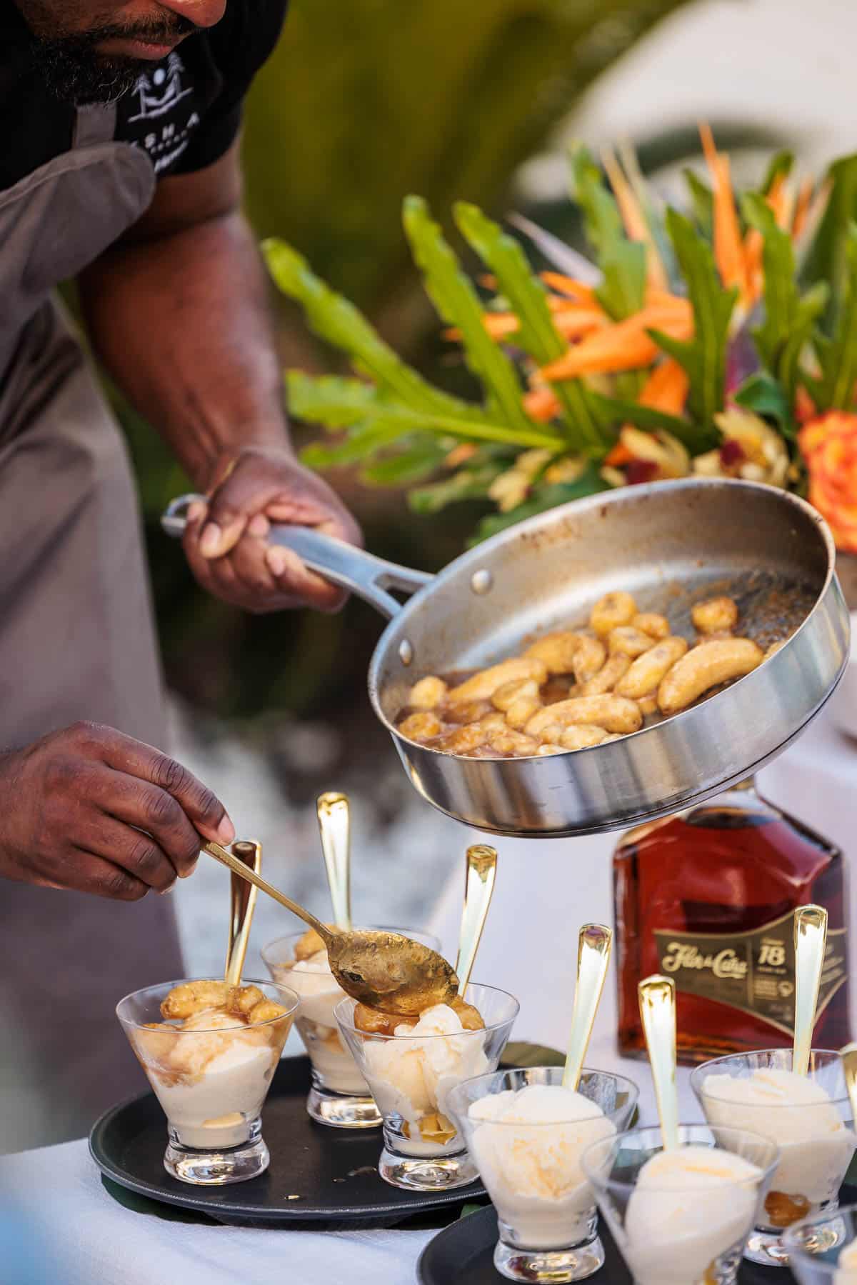 Chef preparing bananas foster with scoops of ice cream.