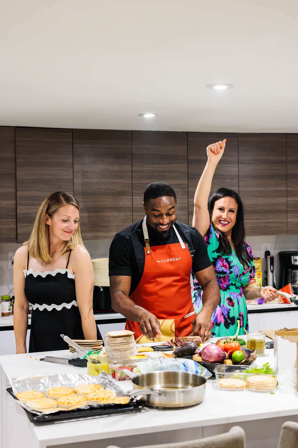 Two women in a kitchen preparing food with a chef.