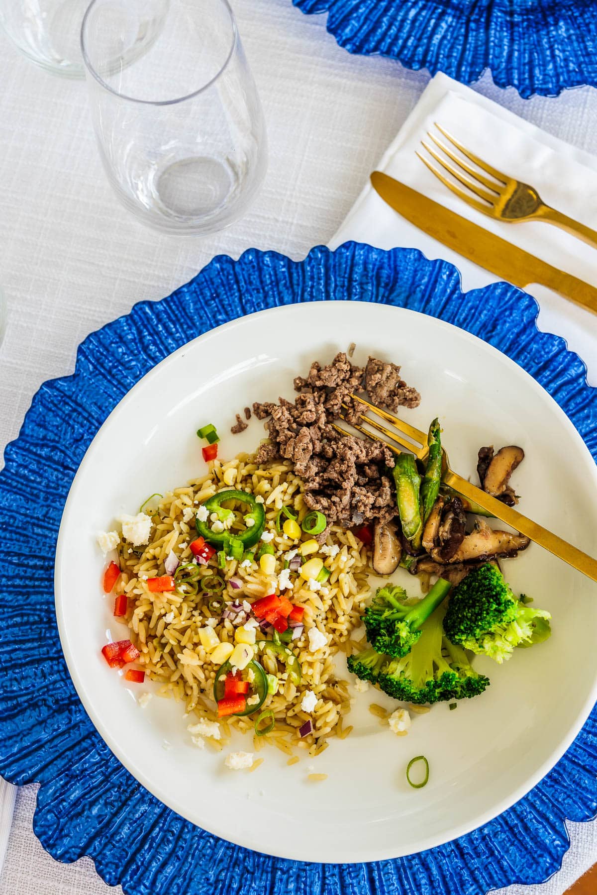 White bowl on a table with rice, ground meat and broccoli.