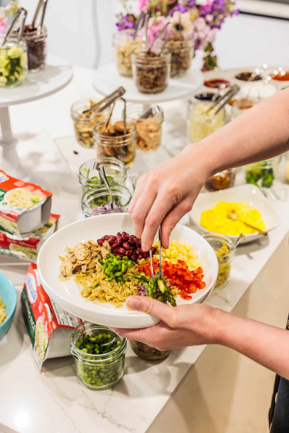 Creating rice bowl recipes with vegetables, beans and rice in a white bowl.