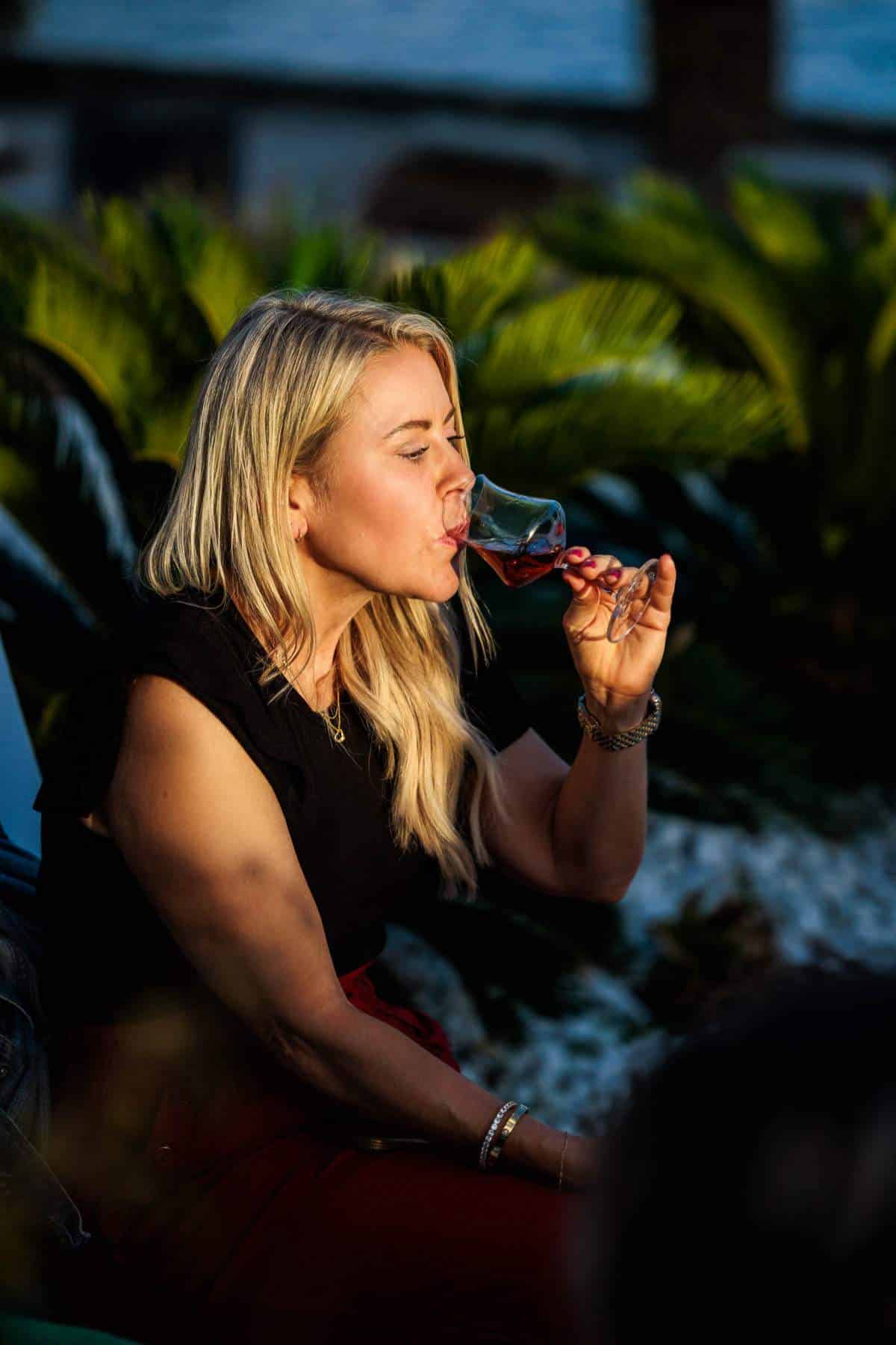 Woman tasting rum from a glass.