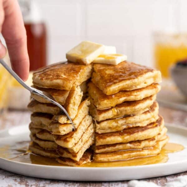 Fork cutting into a stack of pancakes.