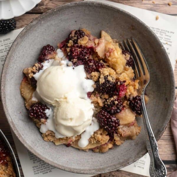 Apple blackberry crumble topped with two scoops of vanilla ice cream.