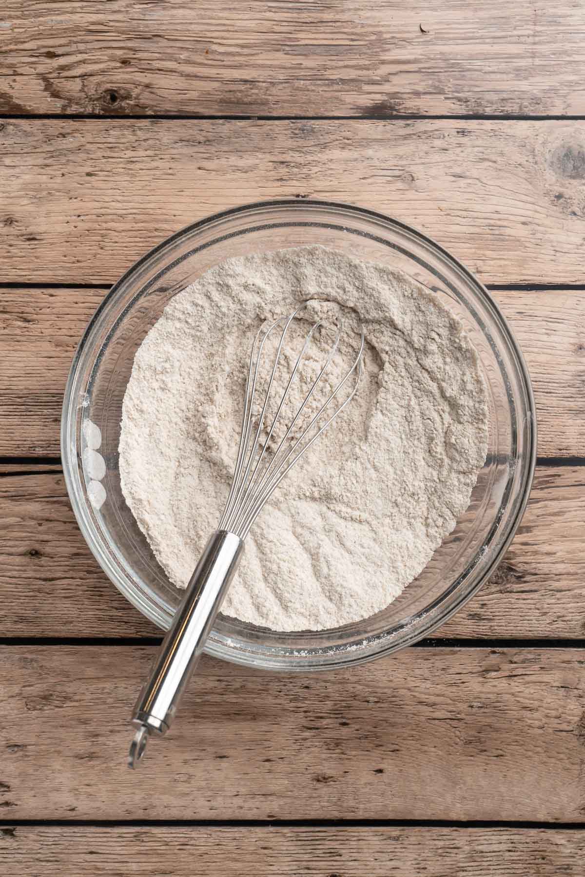 Whisking flour with salt, baking powder, cinnamon and sugars together in a large mixing bowl.