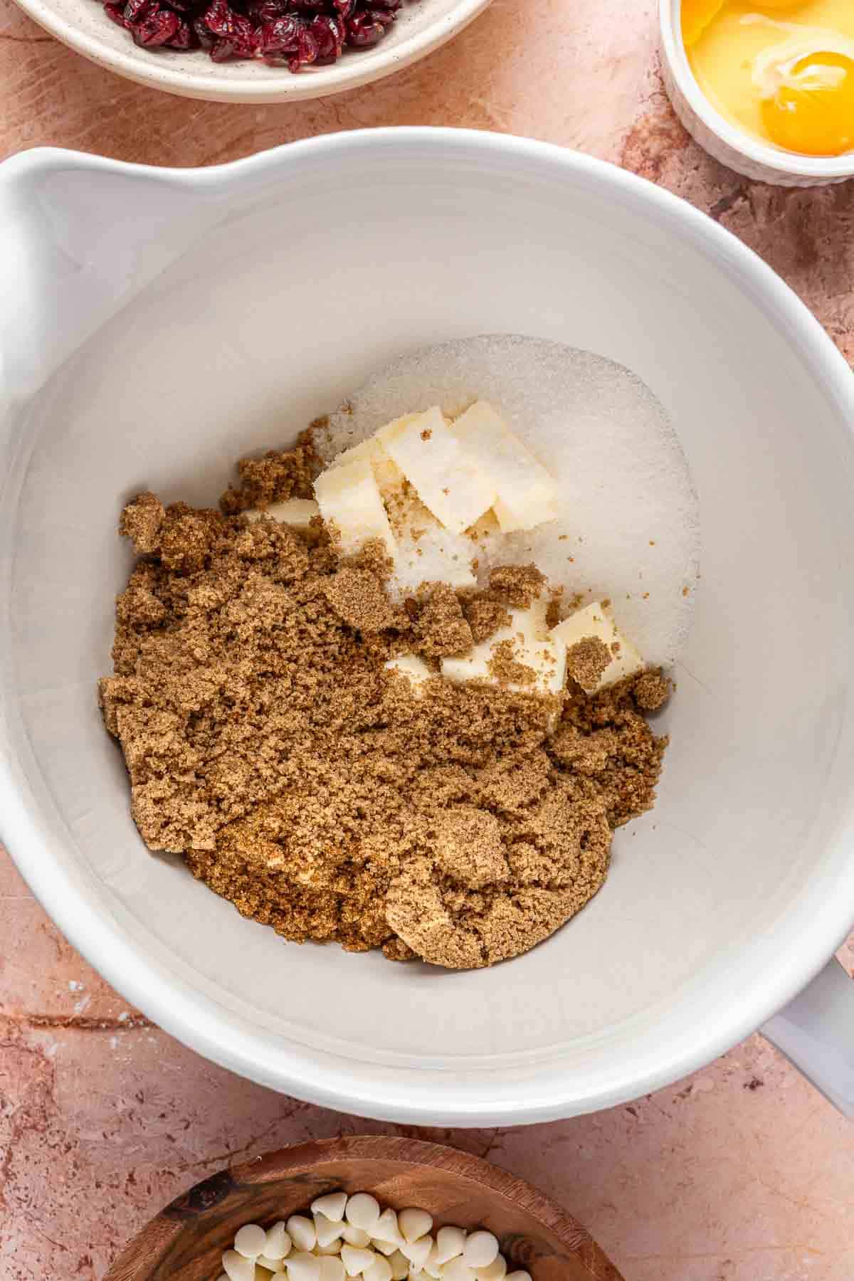 Mixing butter with brown sugar and granulated sugar in a mixing bowl.