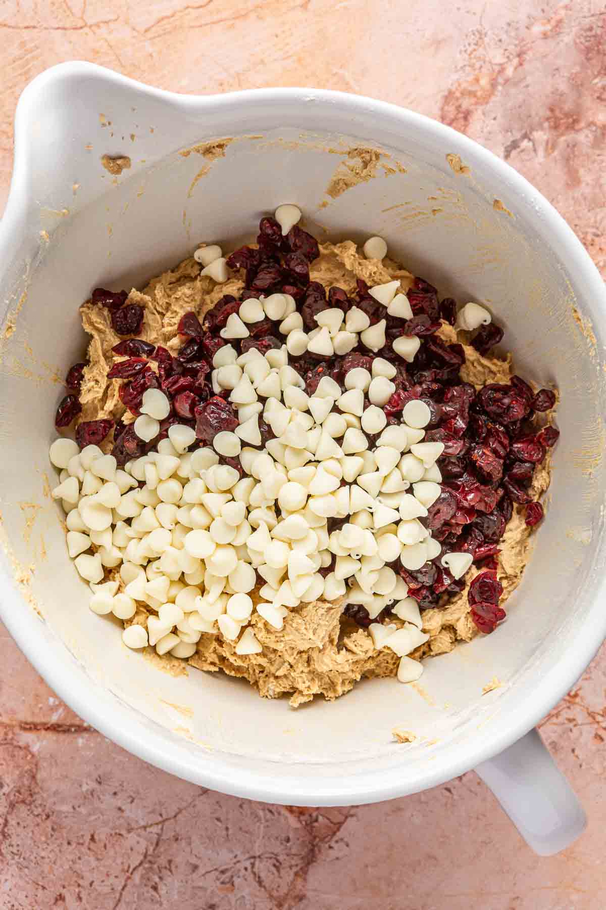 Adding white chocolate chips and dried cranberries to cookie dough.