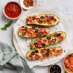 Pizza zucchini boats topped with black olives and mini pepperonis.