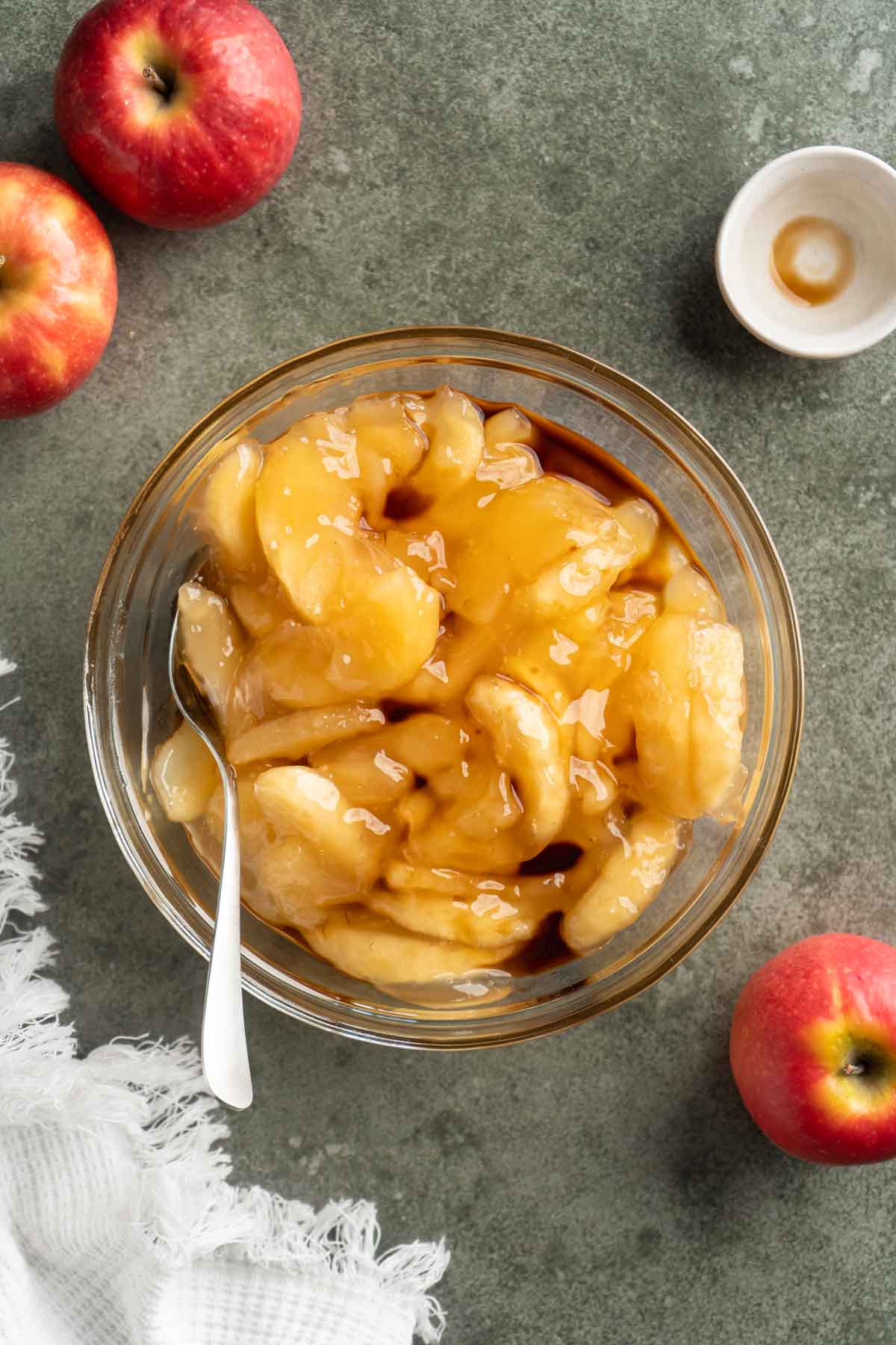 Stirring apple slices with vanilla in a small glass bowl.