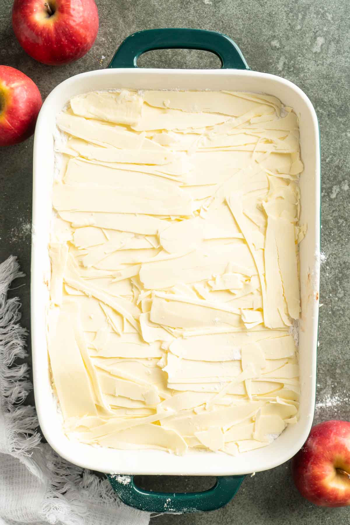 Slices of butter covering apples and dry cake mix.