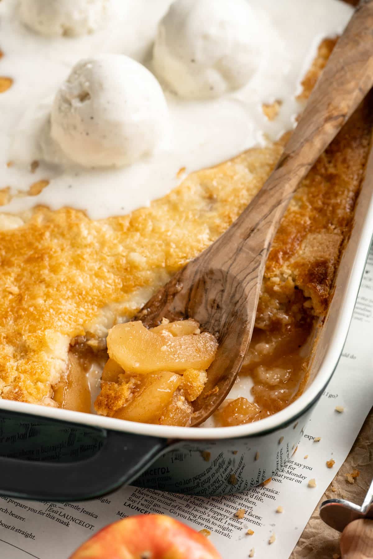 Wooden spoon in a dish with apple dump cake.