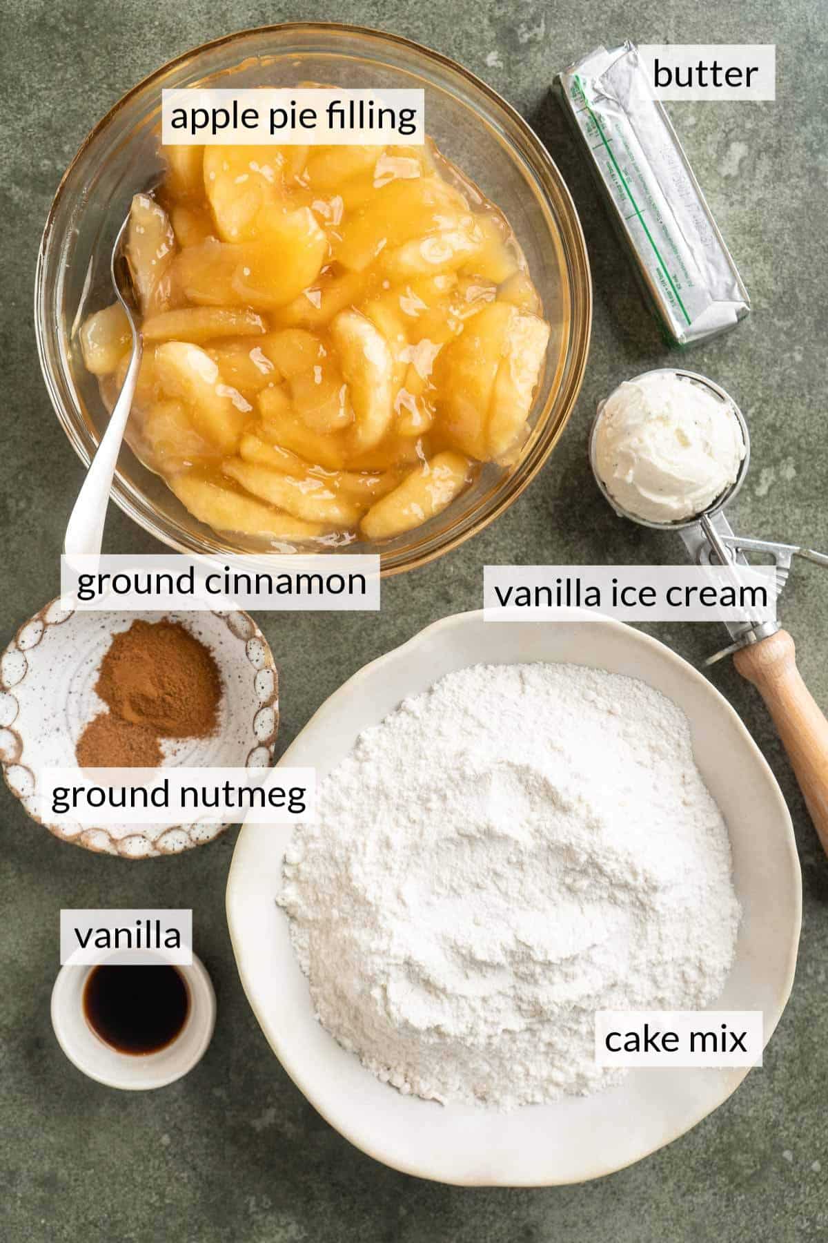 Bowl of dry cake mix, apple pie filling, spices and butter.