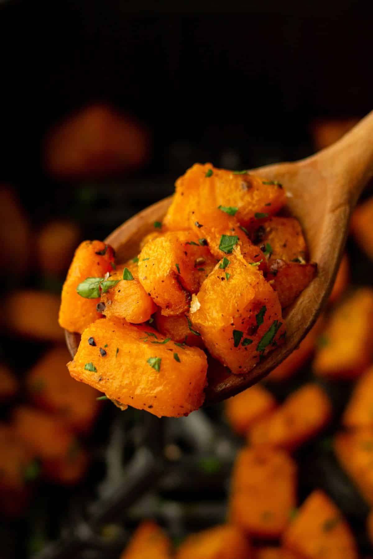 Serving butternut squash with a wooden spoon.