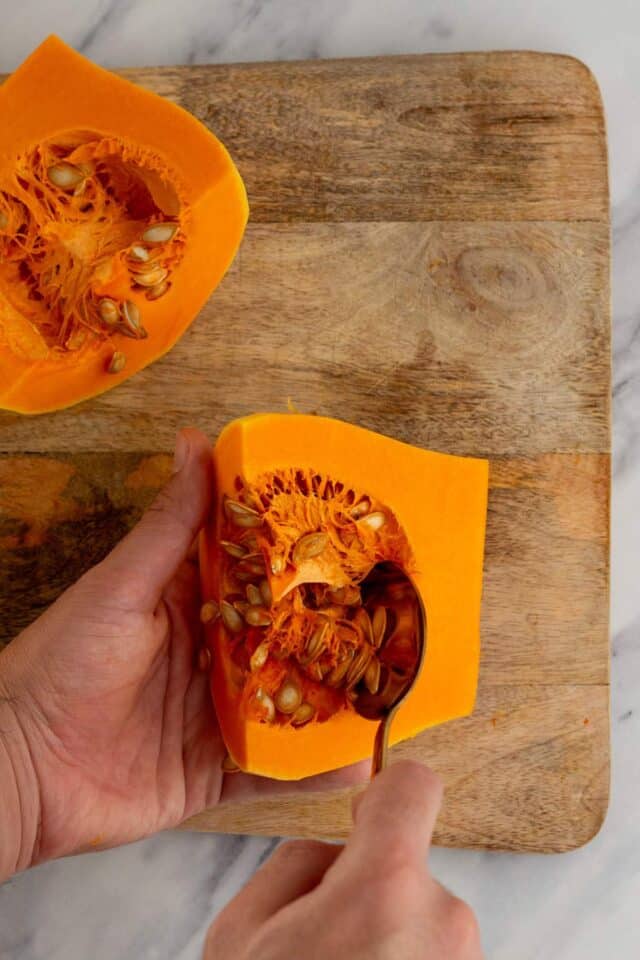 Spooning out the seeds in a butternut squash.