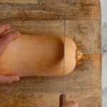 Slicing the top of a butternut squash off with a knife.