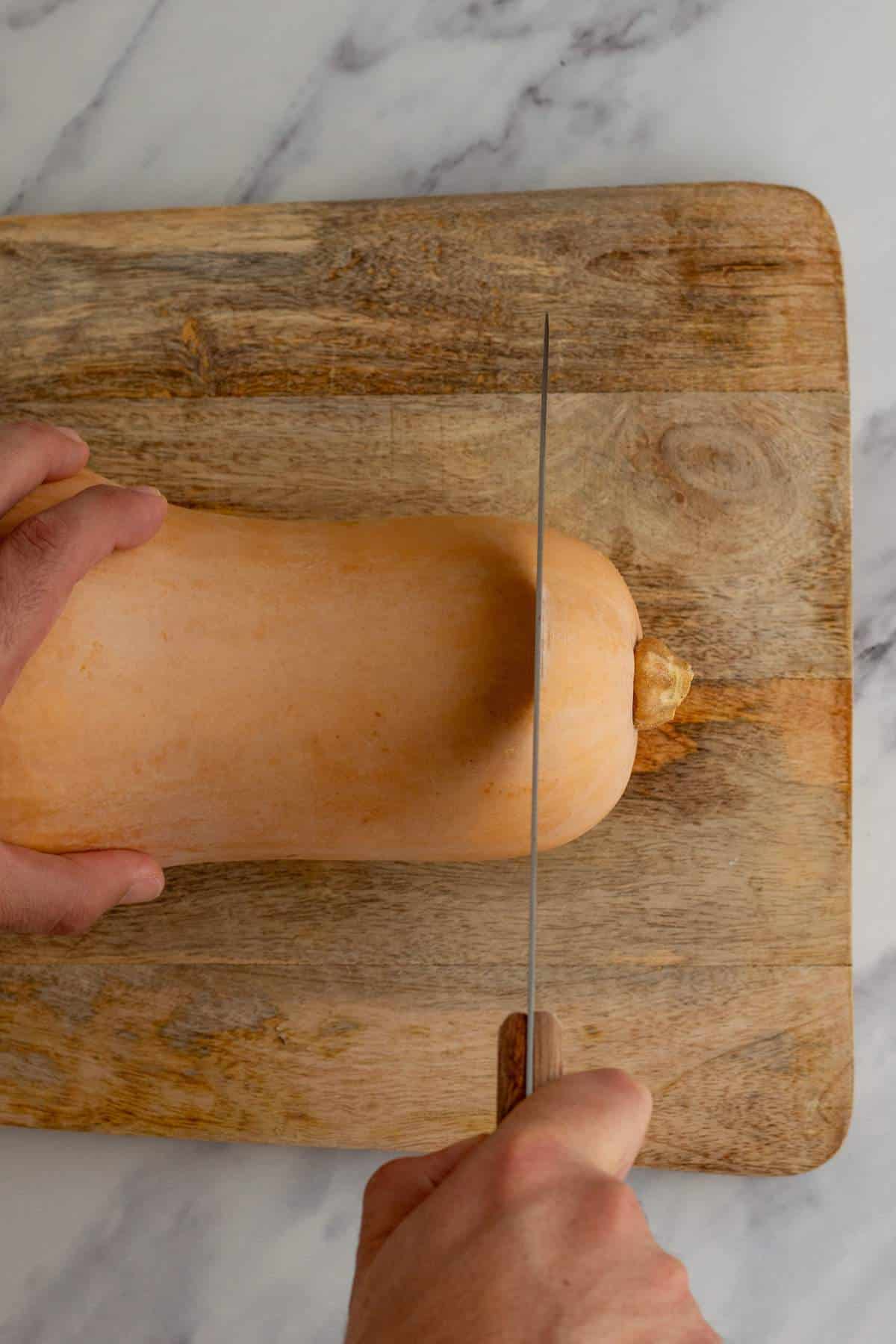 Slicing the top of a butternut squash off with a knife.