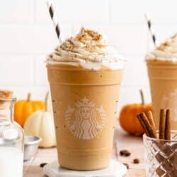 Pumpkin Spice Frappuccino topped with whipped cream and served with a straw.