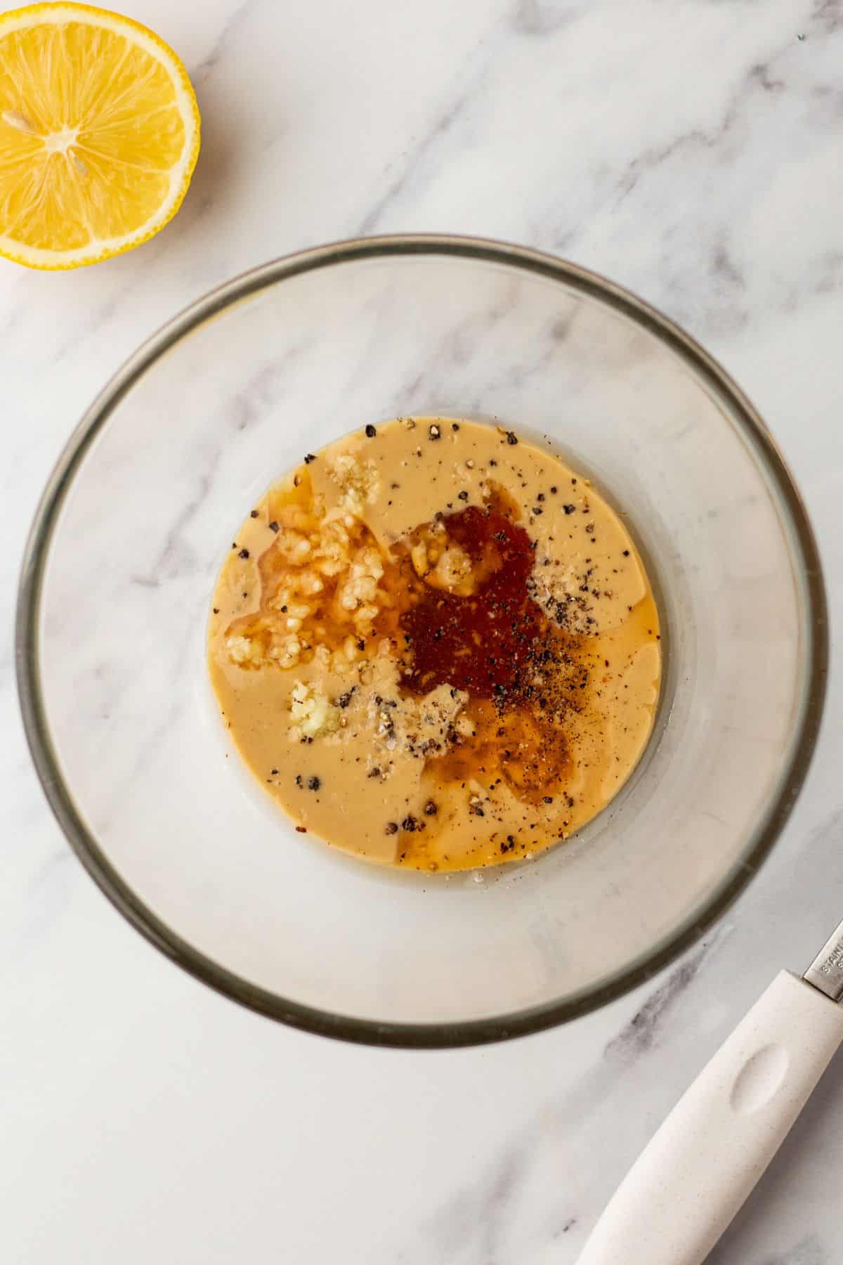 Mixing tahini with maple syrup and garlic.