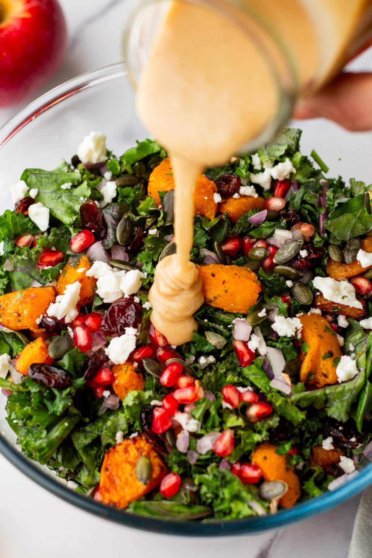 Drizzling tahini dressing over a salad.