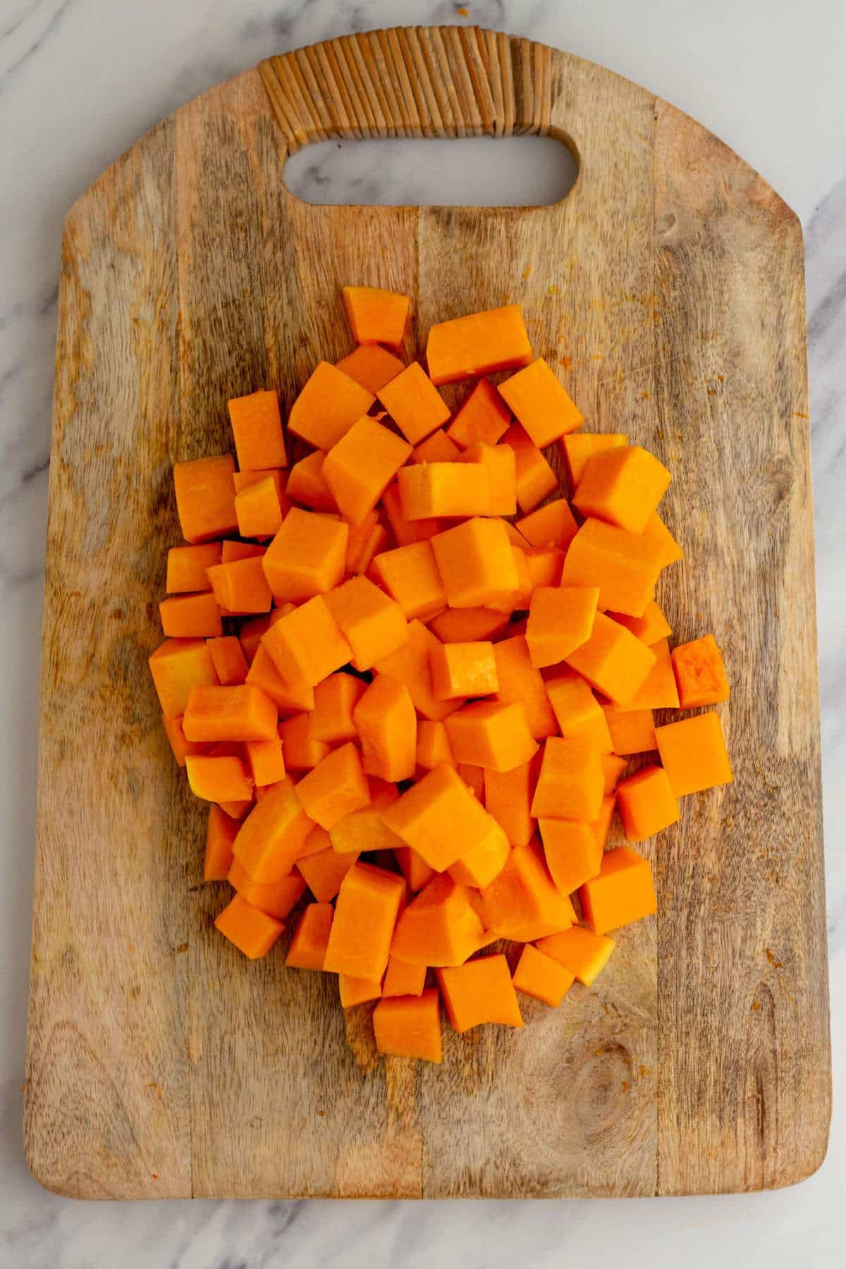 Butternut squash cubed on a cutting board.