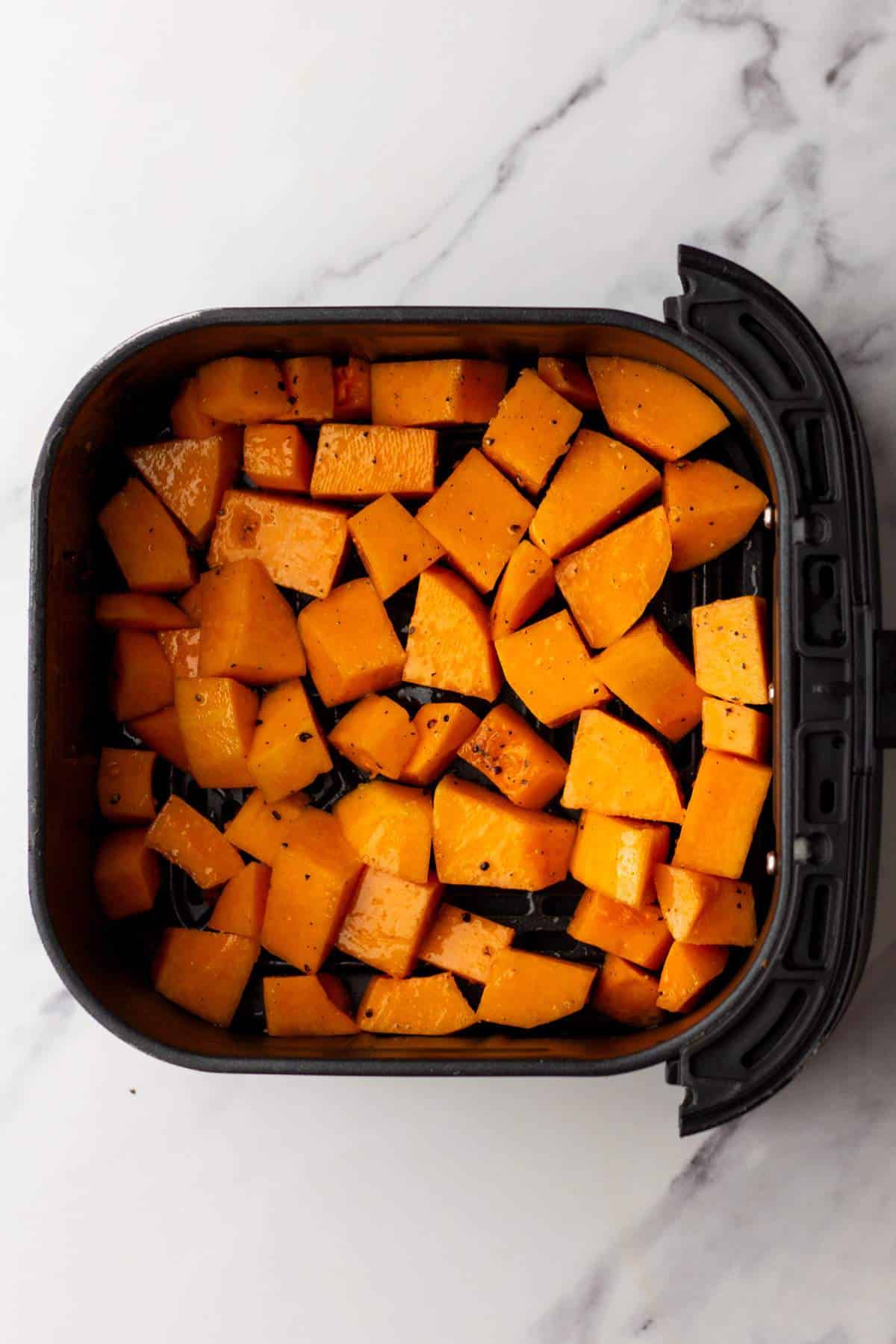 Cubes of butternut squash in an air fryer.