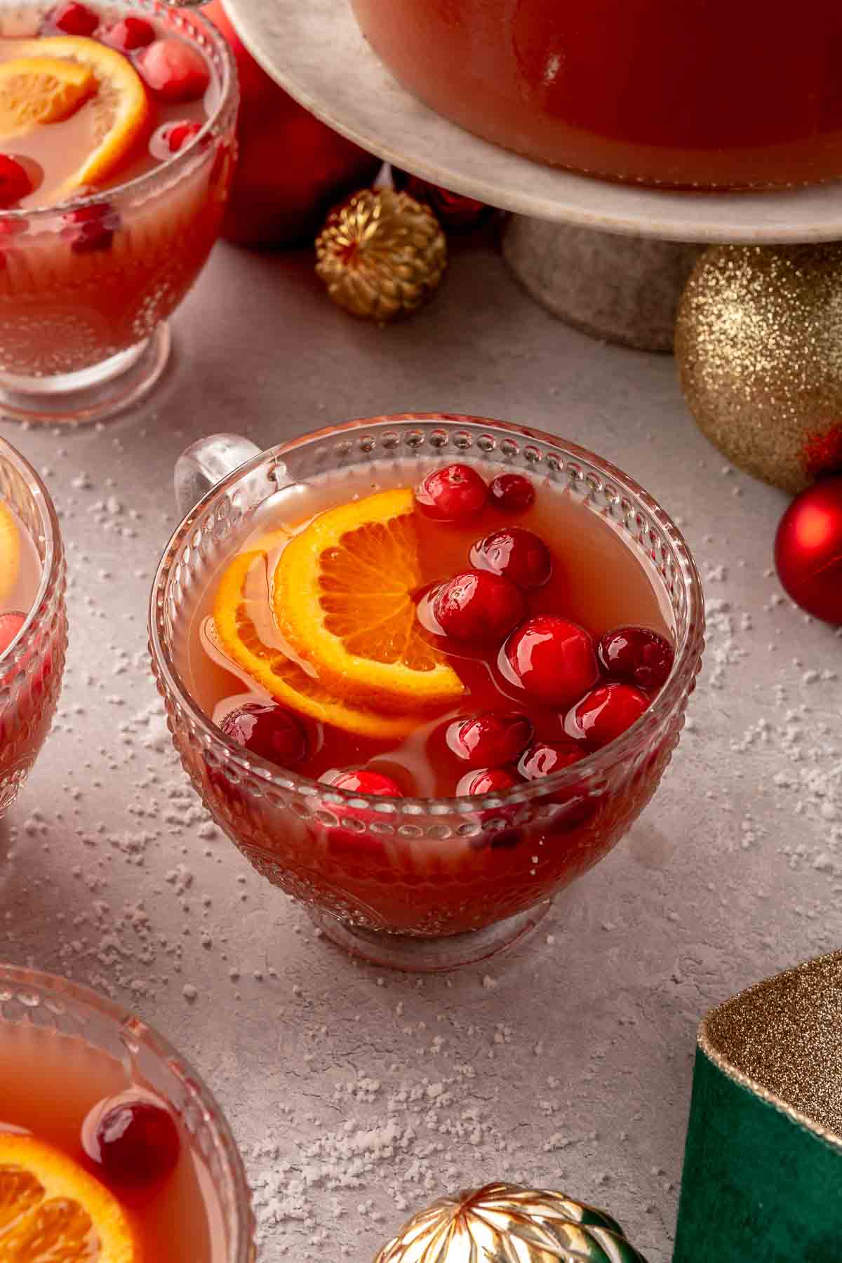 Christmas punch served in a small glass with orange slices and cranberries.