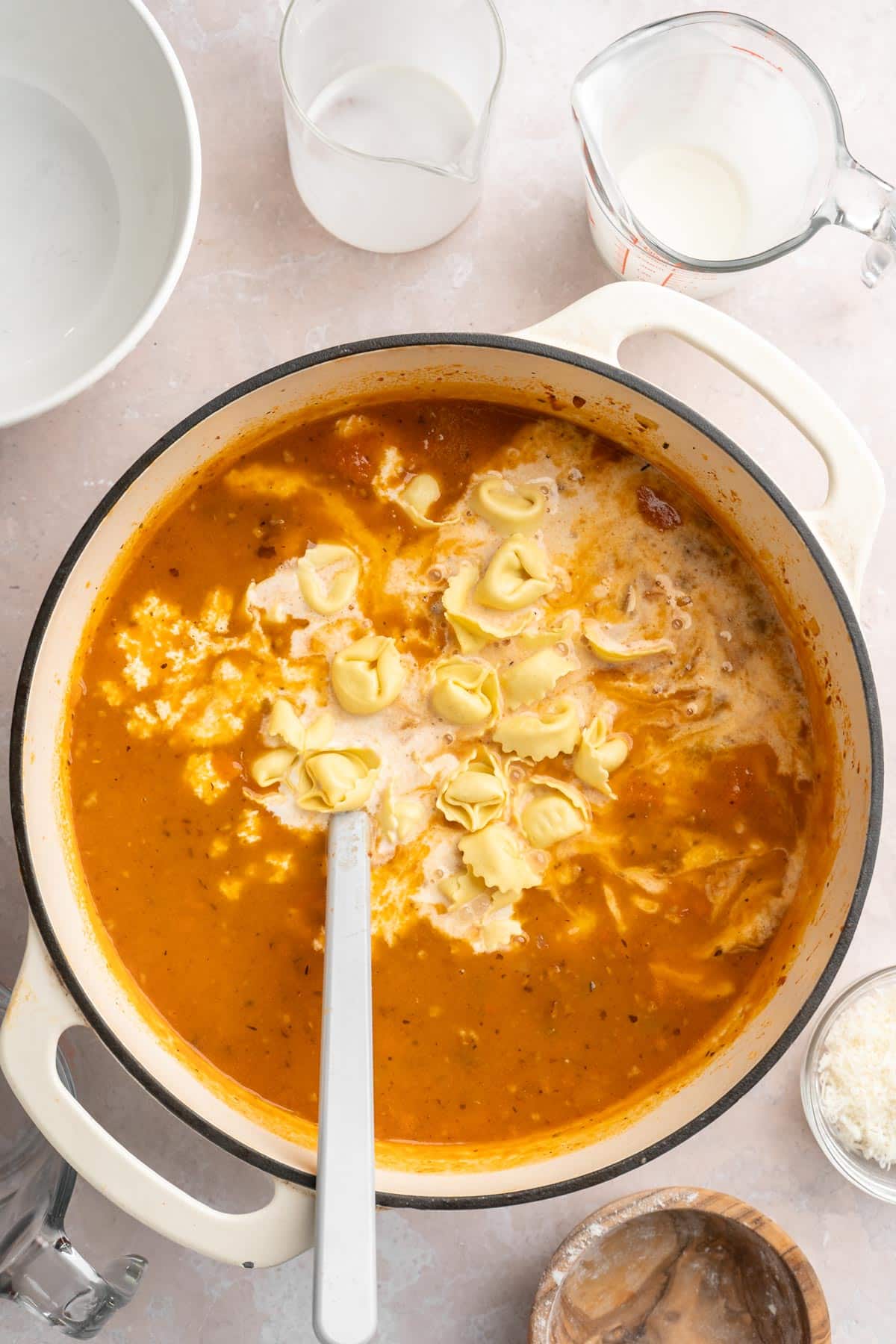 Adding tortellini and cream to soup.