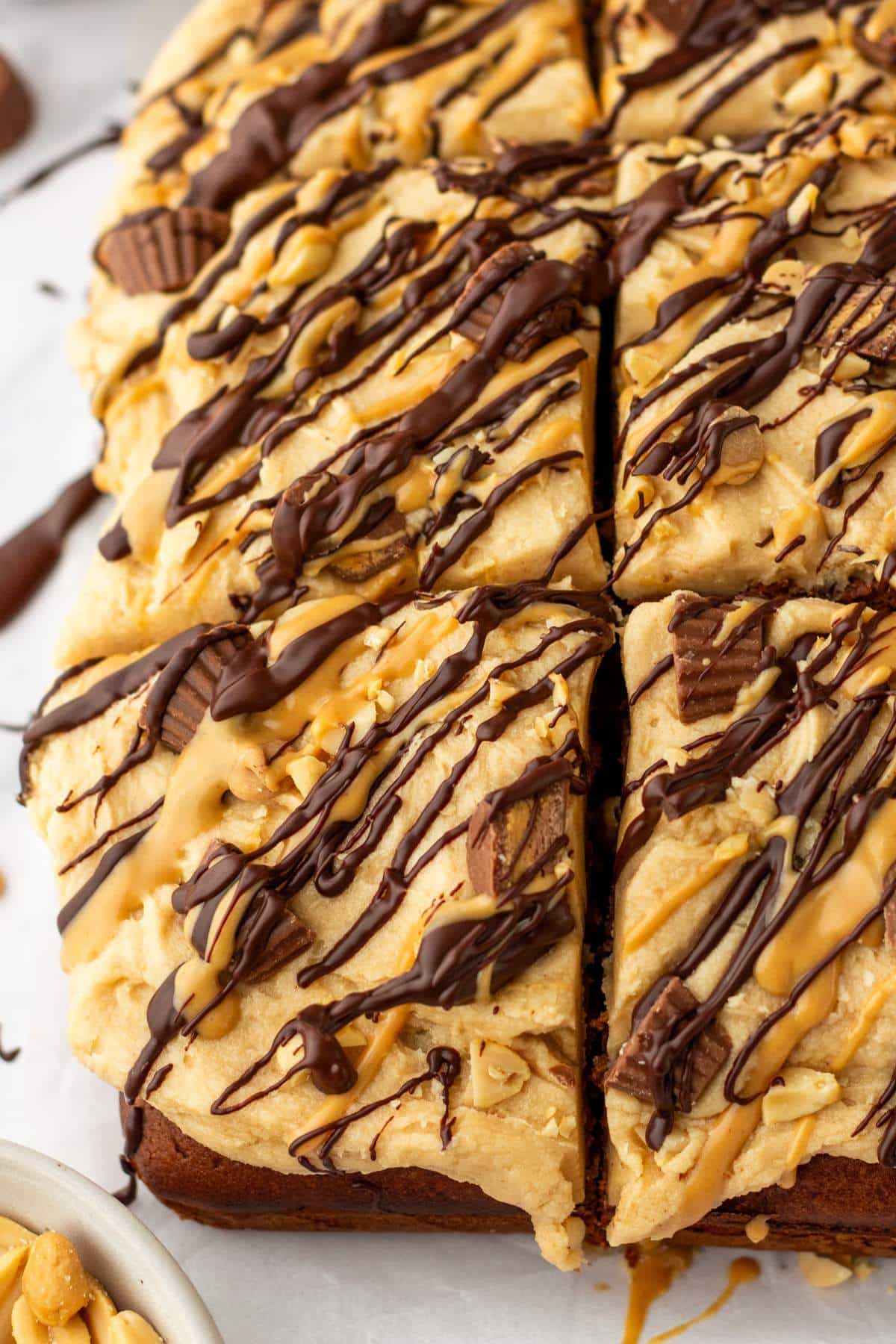 Chocolate peanut butter cake topped with mini Reese's peanut butter cups and chocolate drizzle.