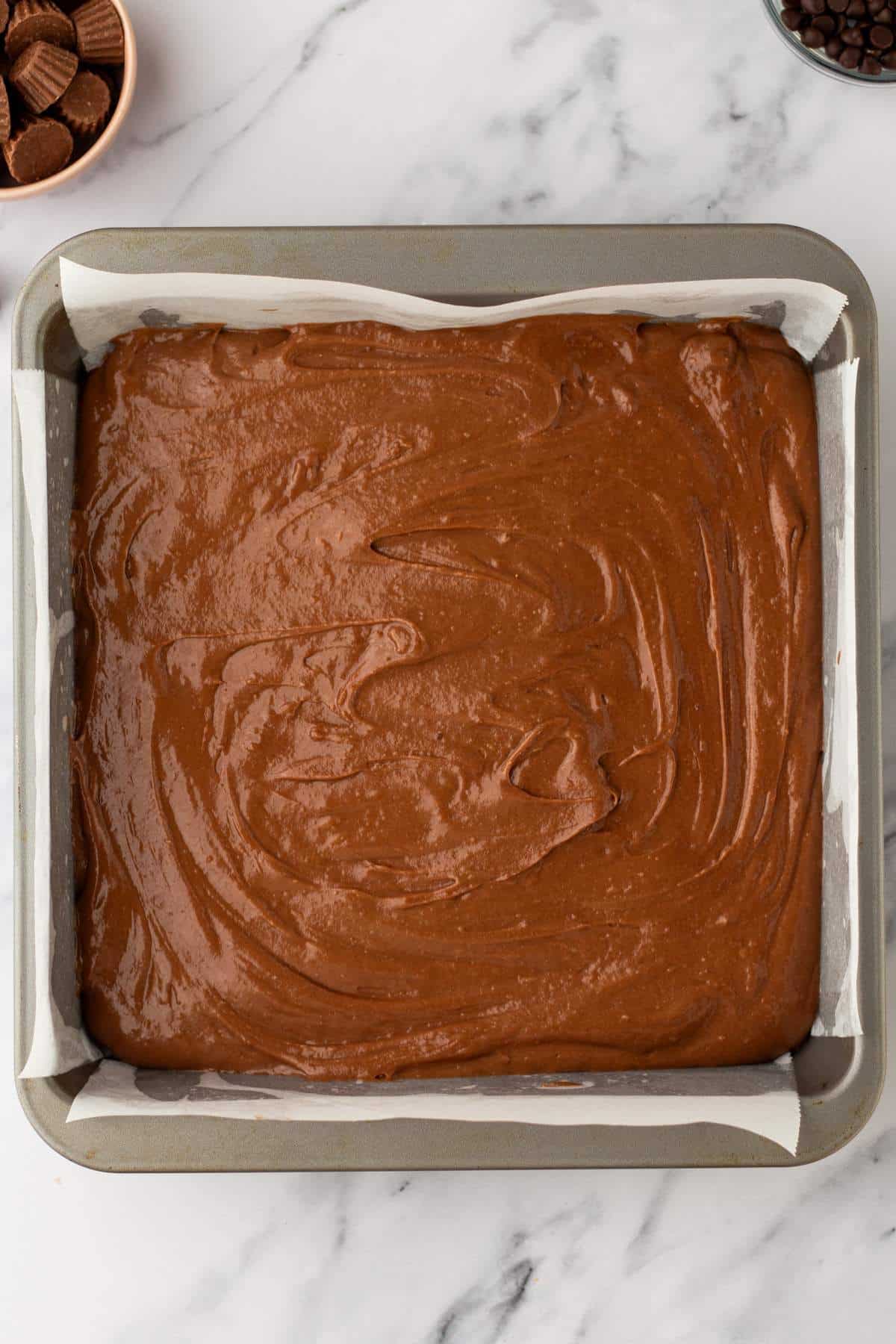 Chocolate cake batter in a square pan.