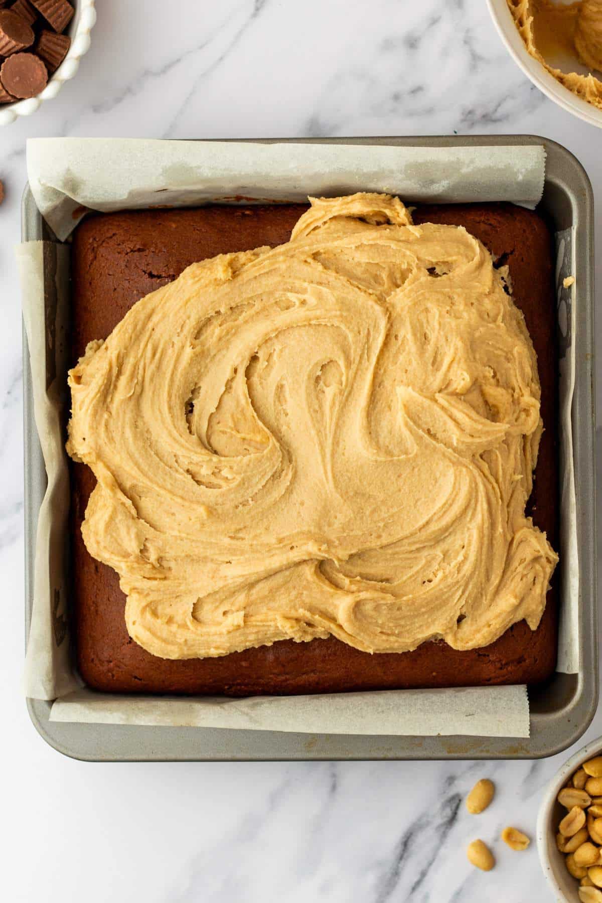 Spreading peanut butter frosting over a chocolate cake.