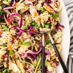 Ramen noodle salad on a large white serving tray with salad spoons.